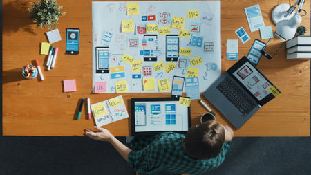Top view of developer working on tablet and writing Ux Ui design for mobile phone interface at note....