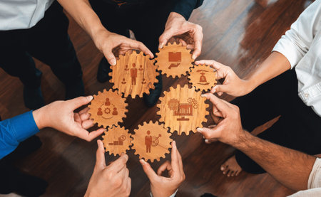 Diverse hands gather around wooden gears with business icons, symbolizing teamwork and collaboration in a professional environment, ideal for corporate projects.の写真素材