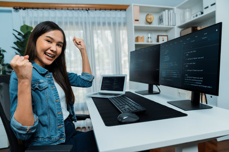 Young Asian IT developer creating raising fist up with successful information on pc with coding program information data application, wearing jeans shirt surround safety analysis screen. Stratagem.の写真素材