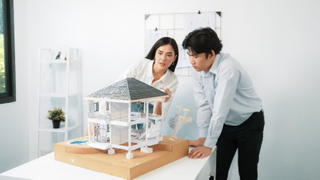 Closeup of young professional skilled architect engineer team focusing on checking the house model structure at modern office. Creative professional design and teamwork concept. Immaculate.の写真素材
