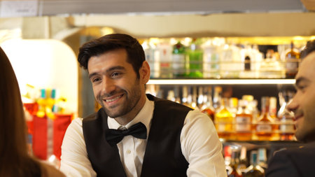 Good looking bartender warm smiling friendly conversation with couple customer at beverage bar counter while serving welcome drink with charm professionalism recommending special menu list. Vinosity.の写真素材