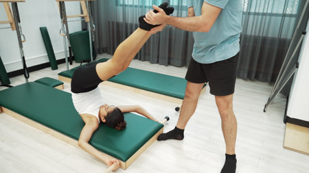 Pilates client practicing leg raises with core engagement during a Pilates session. Woman pose at...