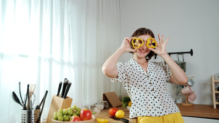 Happy mother chopping at vegetable or making salad and pose at camera. House keeper prepare fresh ingredients while looking at camera. Smart mom cooking at modern kitchen with kitchenware. Pedagogy.の写真素材