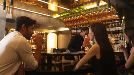Couple making a toast with cocktail paloma and old fashioned at luxurious bar in lively conversation drinks celebrating a special party at vibrant nightclub while friend drinking Margarita. Vinosity.の写真素材