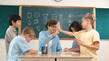 Caucasian teacher giving high five to encourage children to working together. Group of diverse student high five with instructor and present classwork while drawing and writing mind mapping. Pedagogy.の写真素材