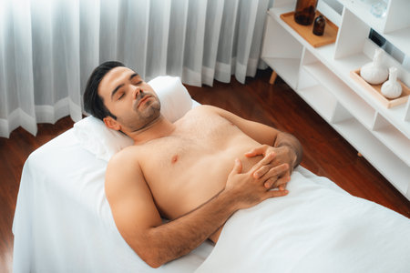 Caucasian man customer enjoying relaxing anti-stress spa massage and pampering with beauty skin recreation leisure in day light ambient salon spa at luxury resort or hotel. Quiescentの写真素材