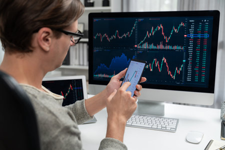 Smart stock investors pointing on screen with smartphone for market stock exchange along with laptop screen in highest dynamic investment rate, focusing data planning at modern workplace. Pecuniary.の写真素材