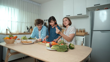 Happy father move to music while cooking food and prepare lunch at modern kitchen. Active dad dancing to song while making healthy food or salad surrounded with vegetable and kitchenware. Pedagogy.の写真素材