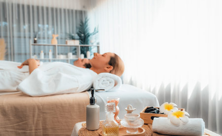 Aromatherapy massage on daylight ambiance or spa salon composition setup with focus decor and spa accessories on blur woman enjoying blissful aroma spa massage in resort or hotel background. Quiescentの写真素材