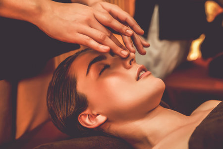 Caucasian woman enjoying relaxing anti-stress head massage and pampering facial beauty skin recreation leisure in warm candle lighting ambient salon spa in luxury resort or hotel. Quiescentの写真素材