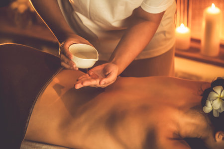 Masseur hands pouring aroma oil on woman back. Masseuse prepare oil massage procedure for customer at spa salon in luxury resort. Aroma oil body massage therapy concept. Quiescentの写真素材