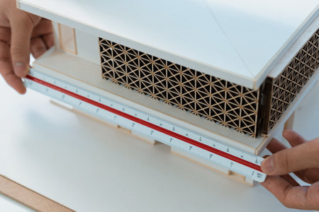 Closeup of professional architect hand measuring house model by using ruler and architectural equipment at modern office. Creative business design concept. Focus on hand. Immaculate.の写真素材