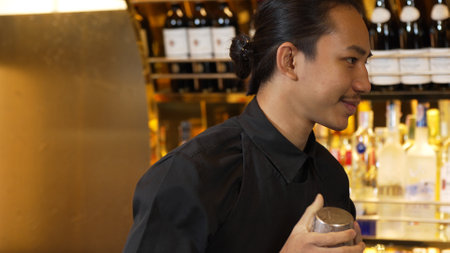 Closeup Asian hand bartender shaking mixed cocktail at luxurious counter preparation for making...