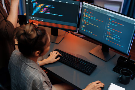 IT developers discussing with point to intelligent website development coder system running data online on pc of two screens with information technology at neon light room at modern office. Infobahn.の写真素材