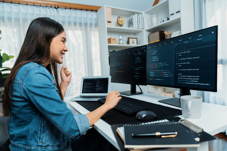 Young Asian in IT developer creating with typing online information on pc with coding program data of website application, wearing jeans shirt. surrounded by safety analysis two screens. Stratagem.の写真素材