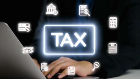 A person using a laptop surrounded by various tax-related icons, representing modern financial management, budgeting, and the importance of digital record-keeping.の写真素材