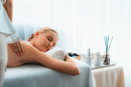 Caucasian woman customer enjoying relaxing anti-stress spa massage and pampering with beauty skin recreation leisure in day light ambient salon spa at luxury resort or hotel. Quiescentの写真素材