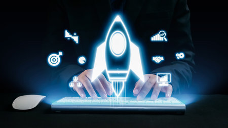 A dynamic scene featuring hands typing on a keyboard, complemented by a glowing rocket launch graphic, symbolizing innovation and business growth in a modern digital workspace.の写真素材