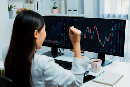 Successful young Asian businesswoman earning highest profit with fist up in exchange stock market on...
