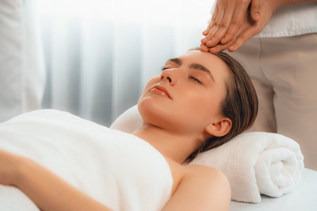 Caucasian woman enjoying relaxing anti-stress head massage and pampering facial beauty skin recreation leisure in dayspa modern light ambient at luxury resort or hotel spa salon. Quiescentの写真素材