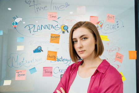 Portrait of young beautiful caucasian businesswoman smiling and posing with confident while looking at camera in front of whiteboard with mind map and colorful sticky notes. Closeup. Immaculate.の写真素材