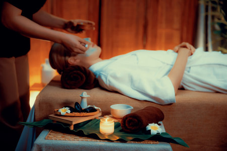 Serene ambiance of spa salon, woman customer indulges in rejuvenating with luxurious face cream massage with warm lighting candle. Facial skin treatment and beauty care concept. Quiescentの写真素材