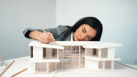 Closeup of professional beautiful young architect engineer focus on measure house model length at...