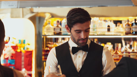 Good looking bartender warm smiling friendly conversation with couple customer at beverage bar counter while serving welcome drink with charm professionalism recommending special menu list. Vinosity.の写真素材