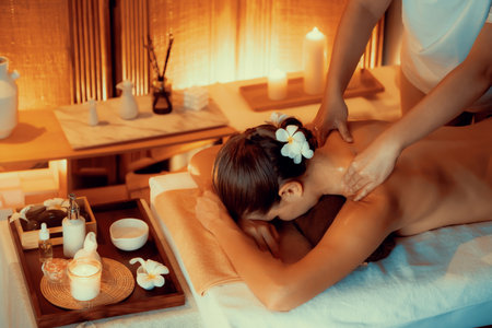 Caucasian woman customer enjoying relaxing anti-stress spa massage and pampering with beauty skin recreation leisure in warm candle lighting ambient salon spa at luxury resort or hotel. Quiescentの写真素材