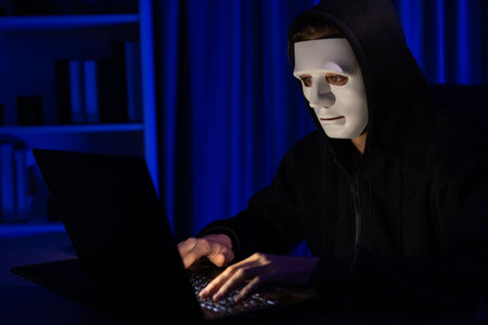 White criminal anonymous mask installing coding password encryption by programming hack, trying to make insecure thorough privacy taking massive database on computer for ransom to company. Pecuniary.の写真素材