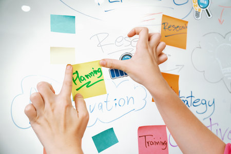 Closeup of professional businesswoman hand put and stick the colorful sticky notes on whiteboard while presenting business plan. Creative business meeting and brainstorming concept. Immaculate.の写真素材