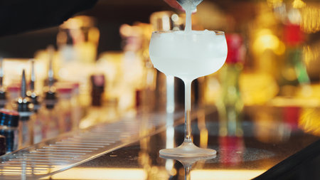 Closeup hand bartender using strainer in vodka coconut smooth fizzy cocktail at luxurious counter preparation making special to guest at fronted bar. Special refresh showcasing nightlife. Vinosity.の写真素材