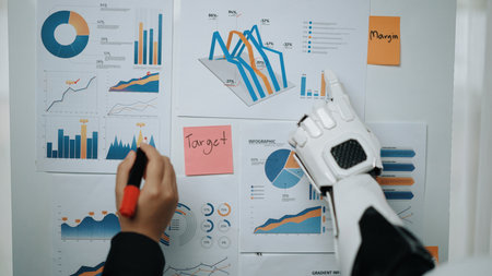 A robotic hand interacts with various charts and graphs on a presentation board, highlighting key metrics and targets essential for effective business analysis.の写真素材