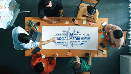 A diverse team engages in a collaborative meeting around a modern workspace table, analyzing social...