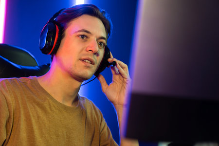 Host channel of gaming smart streamer playing online game to be winner, wearing headphone with viewers live steaming on media social online for selected team competition at neon light room. Pecuniary.の写真素材