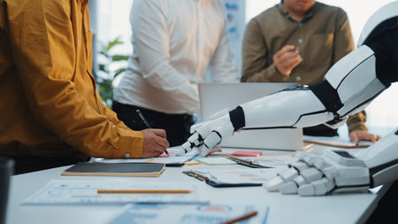A scene depicting a modern office meeting where a robotic arm assists a human team. This image illustrates advanced technology in collaboration and innovative approaches to teamwork.Noogenesisの写真素材