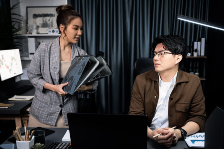 Serious face of working sales manager with secretary taking overworked folder paper at over late...