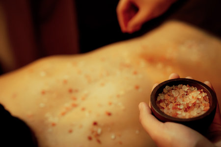 Closeup man customer having exfoliation treatment in luxury spa salon with warmth candle light ambient. Salt scrub beauty treatment in Health spa body scrub. Quiescentの写真素材