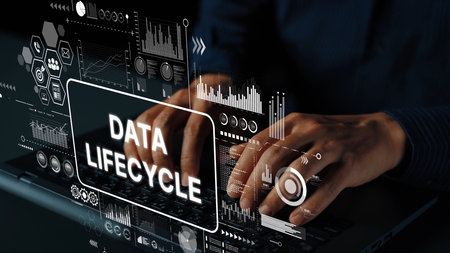Hands Typing on Laptop with Data Lifecycle Concept and Technology Graphics Overlay in Dark Environment. Asymptotic smart data analytic.の写真素材