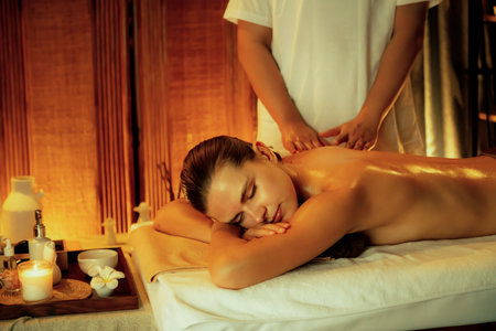 Caucasian woman customer enjoying relaxing anti-stress spa massage and pampering with beauty skin recreation leisure in warm candle lighting ambient salon spa at luxury resort or hotel. Quiescentの写真素材