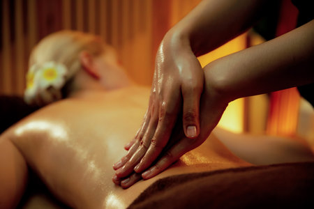 Closeup woman customer enjoying relaxing anti-stress spa massage and pampering with beauty skin recreation leisure in warm candle lighting ambient salon spa at luxury resort or hotel. Quiescentの写真素材