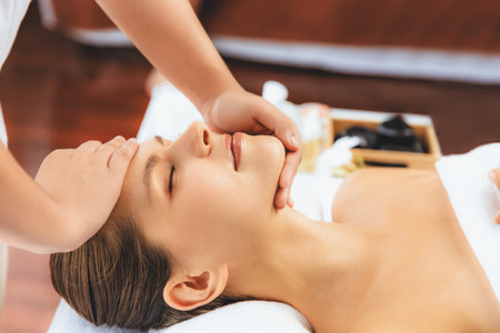 Caucasian woman enjoying relaxing anti-stress head massage and pampering facial beauty skin recreation leisure in dayspa modern light ambient at luxury resort or hotel spa salon. Quiescentの写真素材