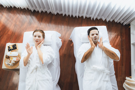 Serene modern daylight ambiance of spa salon, couple customer indulges in rejuvenating with facial skincare mask. Facial skin treatment and beauty cosmetology procedure for face. Quiescentの写真素材
