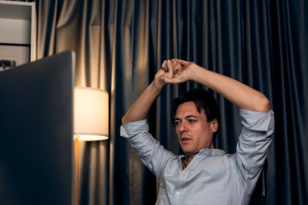 Sales manager working on desk with stretching arm up and down manner at night time at modern home office with monthly sales report for quarter presentation summary of profitable product. Pecuniary.の写真素材