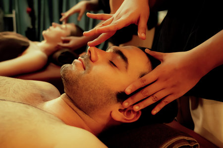 Caucasian man enjoying relaxing anti-stress head massage and pampering facial beauty skin recreation leisure in warm candle lighting ambient salon spa in luxury resort or hotel. Quiescentの写真素材