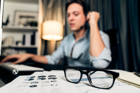 Call center consulting with customers on headphones on monitor in business paragraph with typing on pc with dynamic data marketing analysis planning at modern home office at night time. Pecuniary.の写真素材