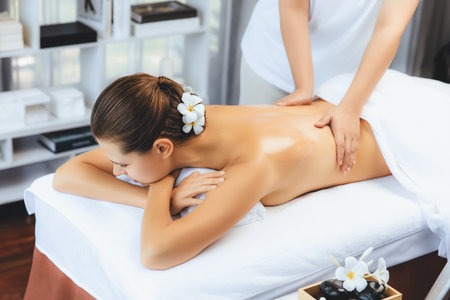 Caucasian woman customer enjoying relaxing anti-stress spa massage and pampering with beauty skin recreation leisure in day light ambient salon spa at luxury resort or hotel. Quiescentの写真素材