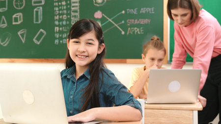 Asian girl looking at camera while coding engineering prompt. Multicultural student learning about generated AI while teacher teaching about system or checking classwork at STEM class. Pedagogy.の写真素材