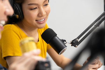 Focusing smiling radio influencer host beautiful woman in yellow shirt wearing headphones with mic...