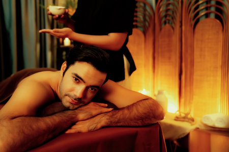 Masseur hands pouring aroma oil on man back. Masseuse prepare oil massage procedure for customer at spa salon in luxury resort. Aroma oil body massage therapy concept. Quiescentの写真素材